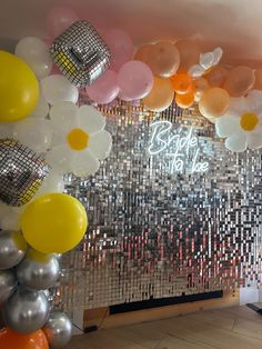 balloons and confetti are hanging from the ceiling in front of a mirrored wall