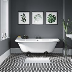 a white bath tub sitting next to a toilet in a bathroom under two framed pictures