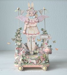 an angel figurine is standing on top of a cart with flowers and butterflies