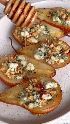 several slices of pears with cheese and herbs on them, being drizzled with honey