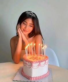 a woman sitting in front of a cake with candles on it