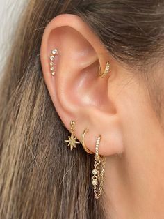 a close up of a person wearing gold ear piercings with stars and moon designs on them