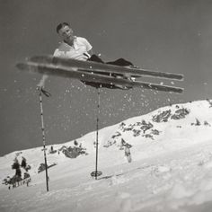 a man flying through the air while riding skis on top of snow covered ground