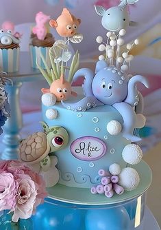 there is a blue cake with sea animals on it and pink flowers in the background