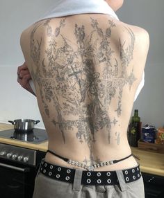 the back of a woman with tattoos on her body and behind her is a stove