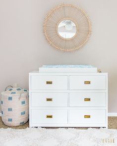 a white dresser sitting next to a round mirror