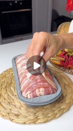 a person is cutting meat into pieces on a tray with other foods in the background