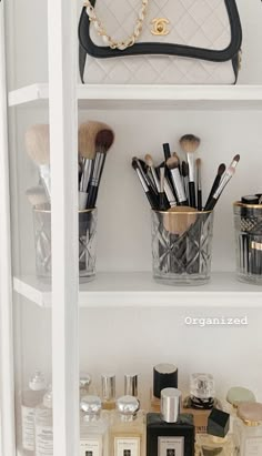 a white shelf filled with lots of makeup brushes and other cosmetics items on top of it