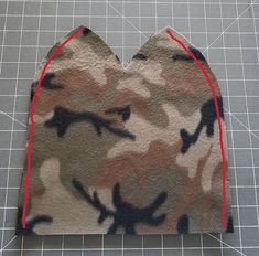 a heart - shaped piece of fabric with red stitching on the edges and camouflage print