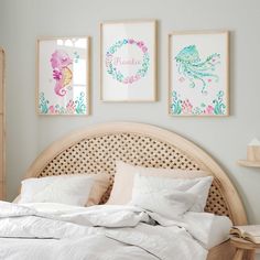 a bed with white sheets, pillows and pictures on the wall above it's headboard