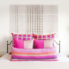 a bed with pink and orange pillows on top of it