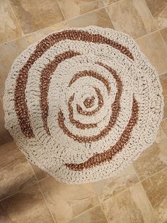 a crocheted round rug on the floor with brown and white circles around it