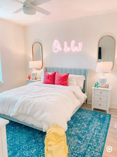 a bedroom with a blue rug, white bedding and two mirrors on the wall