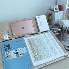 an open book sitting on top of a desk next to a laptop computer and other office supplies