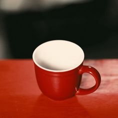 a red and white coffee cup sitting on top of a wooden table