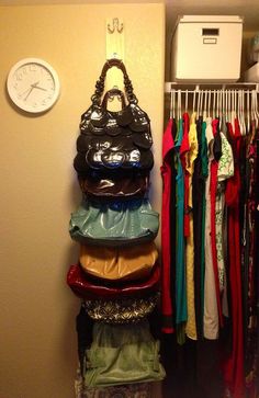 a stack of purses sitting on top of a rack next to a wall mounted clock