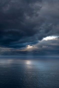 the sky is filled with dark clouds over the ocean