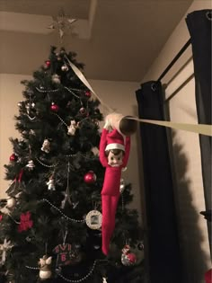 a christmas tree is decorated with ornaments and a doll hanging from it's top