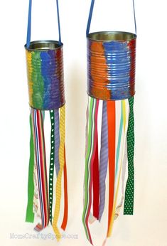 two tin cans with colorful ribbons hanging from the sides and one has a handle on each side