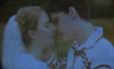 a man and woman kissing each other in front of a tv screen with trees behind them