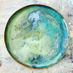 a blue and green plate sitting on top of a wooden table next to a wall