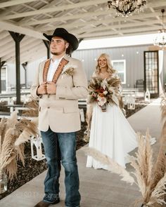 a man in a cowboy hat standing next to a woman wearing a white dress and jacket