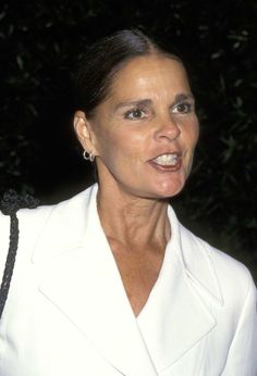 a woman wearing a white suit and earrings