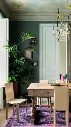 a dining room with a table and chairs in front of a potted palm tree