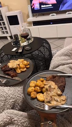 two plates of food on a table in front of a tv