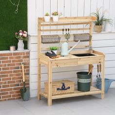 a potting bench sitting next to a brick wall with pots and gardening tools on it