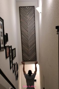 Wooden DIY artwork with herringbone pattern Stairwell Wall Ideas Basement, Black Wall Stairs, Tiled Staircase Wall, Bottom Stair Wall Decor, Diy Stair Wall Decor, Tall Stairway Decorating, Downstairs Wall Ideas, Unique Staircase Wall Decor, Staircase High Ceiling