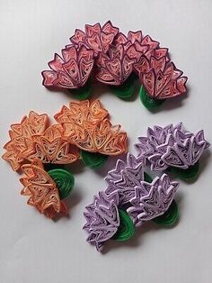 four different colored paper flowers on a white surface