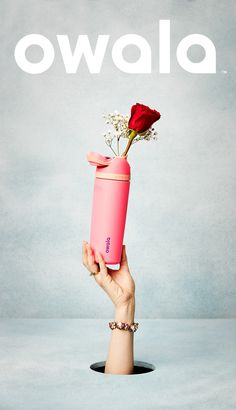 a hand holding a pink tumbler with a red rose in it and the words owala above it