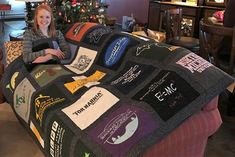 a woman sitting on top of a couch covered in t - shirt shirts next to a christmas tree