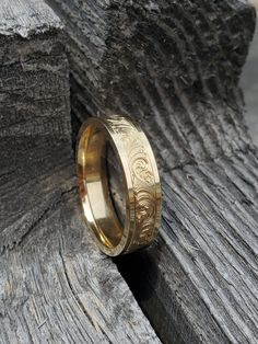 a gold wedding ring sitting on top of a piece of wood