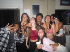 a group of young people standing next to each other holding up their cell phones in the air