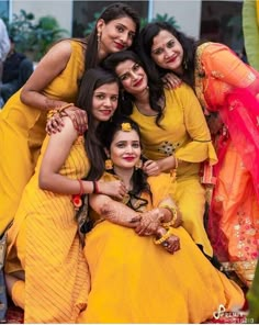 a group of women in yellow dresses posing for a photo with one woman on her lap