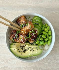 a bowl filled with rice, meat and veggies next to chopsticks