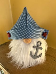 a stuffed toy with an anchor on it's head sitting on a wooden table