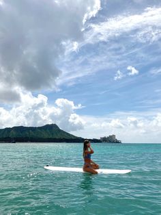 a woman is sitting on a surfboard in the middle of the ocean while looking out to sea