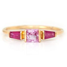 This gorgeous pink Sapphire and tapered Ruby ring reminds of Christian Lacroix's wonderful use of these two colors. The lively pink sapphire is embraced by two extraordinary rubies. The contrast of colors between the two gemstones make them more vivid together that apart.  Hand forged in 18k yellow gold.  For more info Fine Jewelry Pink Emerald-cut Sapphire Ring, Fine Jewelry Pink Sapphire Ring With Emerald Cut, Pink Emerald Cut Ruby Ring In Fine Jewelry, Pink Emerald Cut Sapphire Ring In Fine Jewelry Style, Emerald Cut Pink Ruby Ring In Fine Jewelry Style, Pink Emerald Cut Sapphire Ring Fine Jewelry, Pink Multi-stone Sapphire Ring In Fine Jewelry Style, Pink Multi-stone Sapphire Ring, Fine Jewelry, Pink Sapphire Three-stone Jewelry