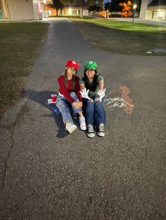 two young women sitting on the side of a road