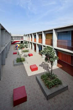 an empty courtyard with benches and plants on the ground, in front of two buildings