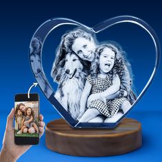 a person holding a cell phone in front of a heart shaped photo frame with a dog on it