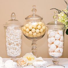 there are many different types of candies in glass containers and vases on the table