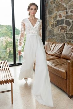 a woman standing in front of a window wearing a white dress