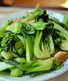 a white plate topped with broccoli and other vegetables on top of a table