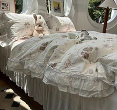 a bed with white ruffled bedspread and teddy bears on the comforter