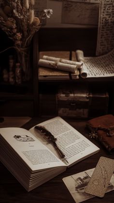 an open book sitting on top of a wooden table next to other books and papers