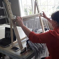 a woman working on an art project with a laptop computer and weaving machine in front of her